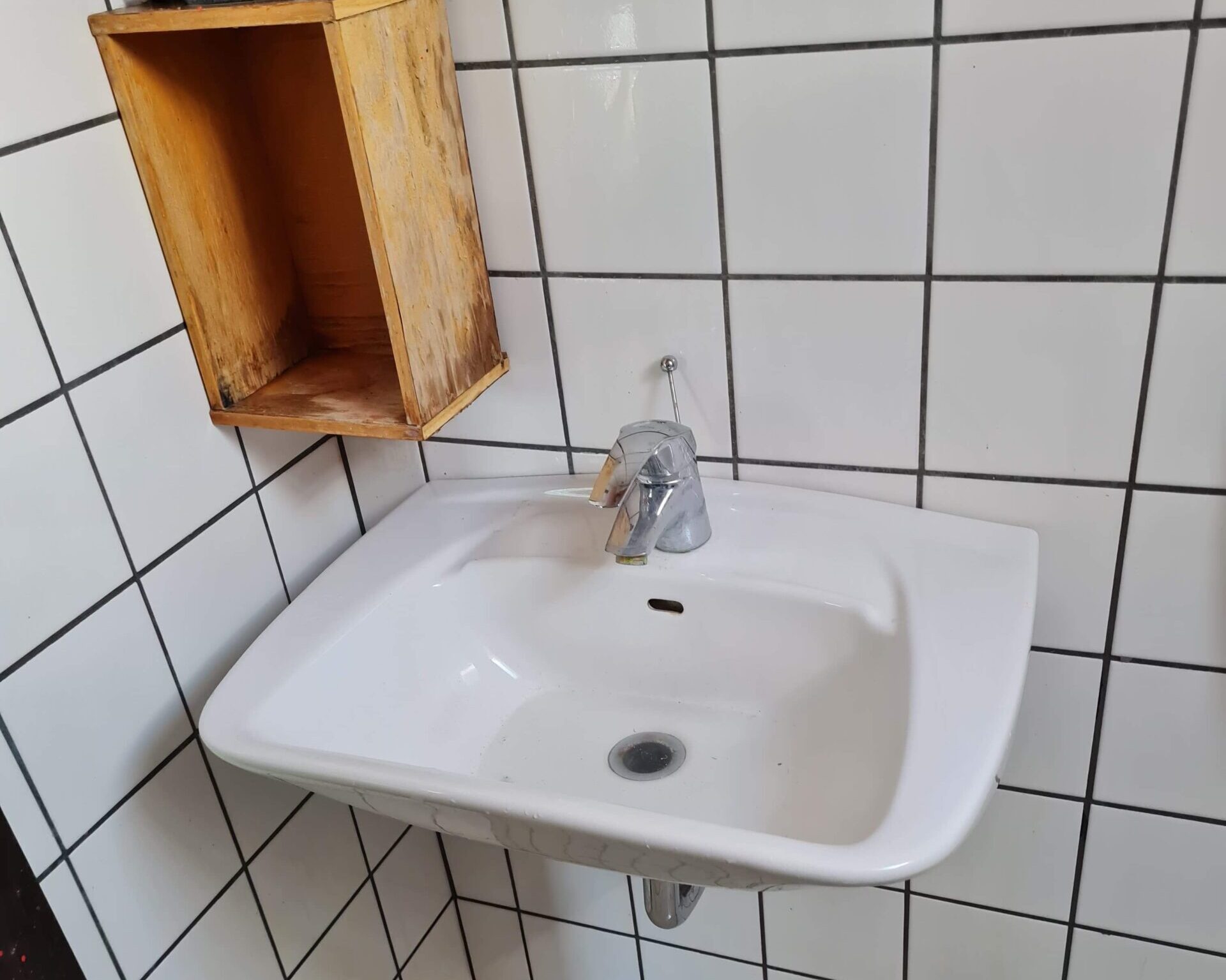 Offentligt toilet med hvid vask og hvide fliser efter graffitirens af Rensfyn